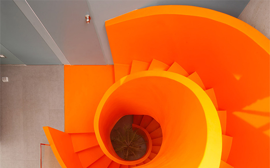 Vue plongeante sur un escalier colimaçon métallique sculptural aux lignes circulaires