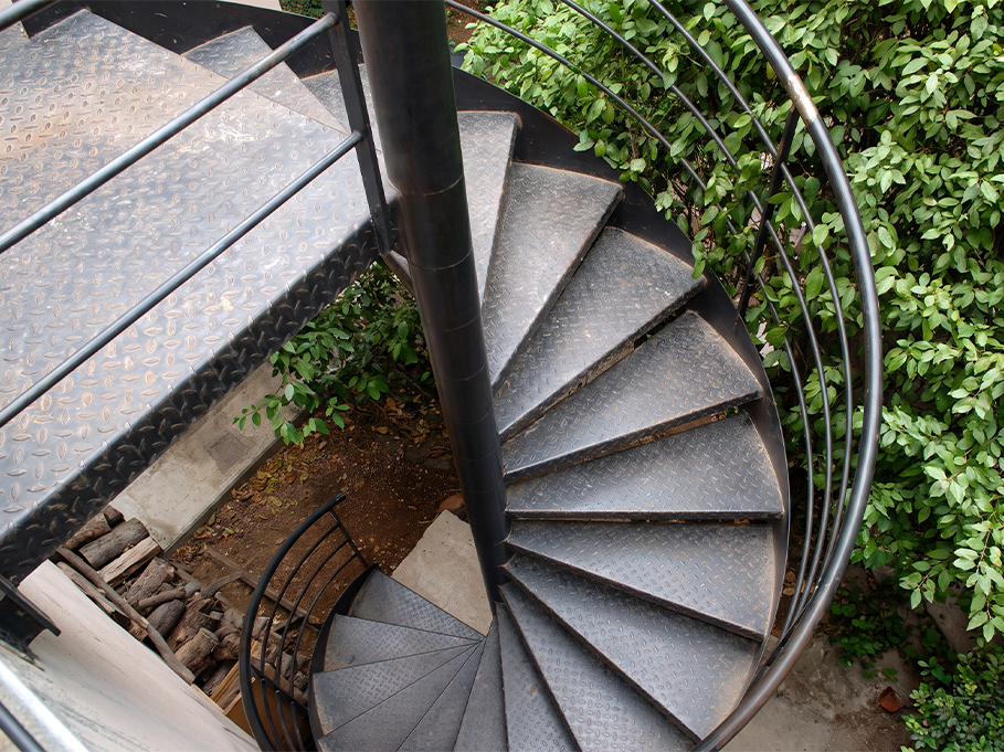 Escalier en colimaçon métallique extérieur avec mât central, marches en acier antidérapantes et garde-corps courbe