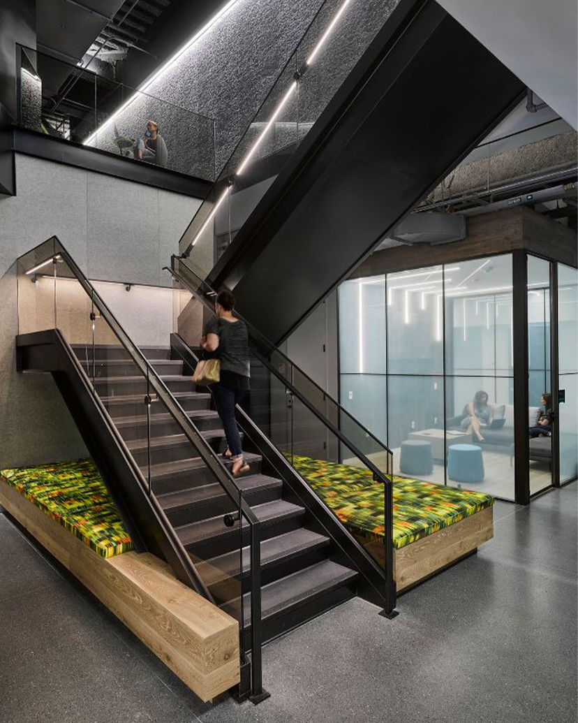 Escalier métallique sur mesure avec garde-corps en verre dans un showroom contemporain